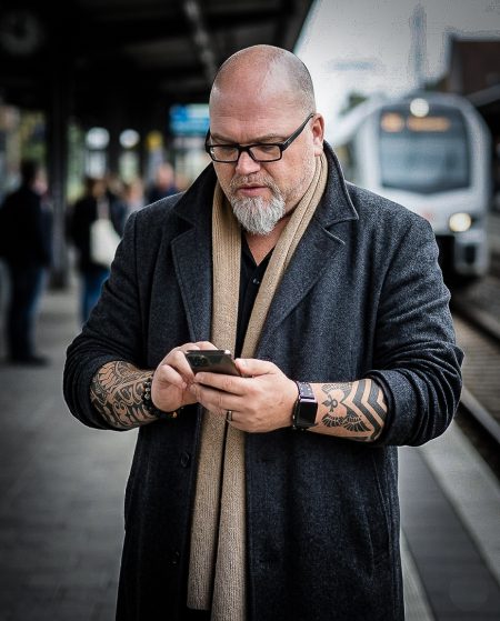 Robert James Perkins wearing glasses and smartphone on the platform